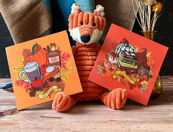 Cartes Recettes double sur lesquels on aperçoit des illustrations d'automne. Décor avec des fleurs séchées, une citrouille, une peluche renard et une écharpe à carreaux. Citrouille, latte, chocolat chaud, bougie, canelle, feuilles mortes