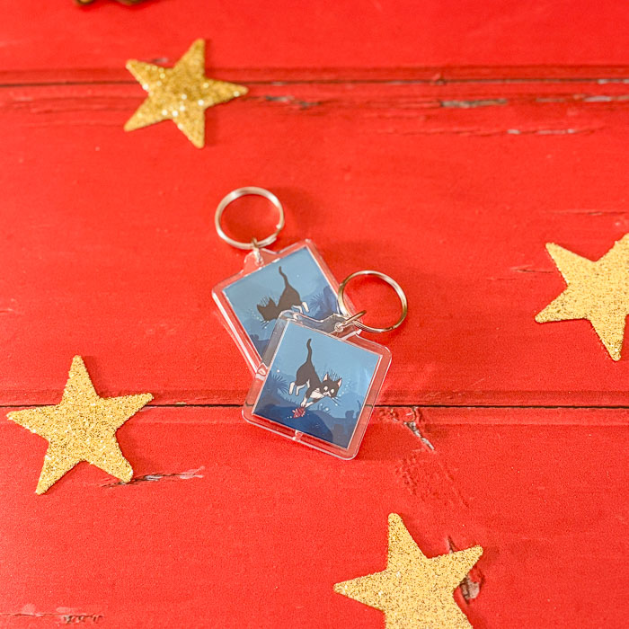 Porte-clés illustré d’un chat en tenue de plongée faisant de la pêche sous-marine, jeu de mots “poisson-chat”.