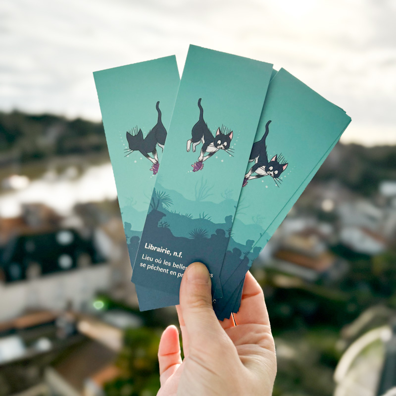 Marque-page illustré recto verso représentant un petit chat sous l’océan attrapant un poisson, avec une définition poétique du mot librairie.