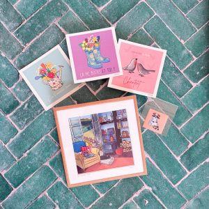 Contenu du Lot Printemps — illustration encadrée, mini cartes et magnet sur fond de carreaux verts.